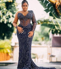 Woman wearing a dark blue beaded evening gown outdoors with greenery in the background